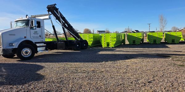 Patriot Solutions truck beside green roll-off dumpsters